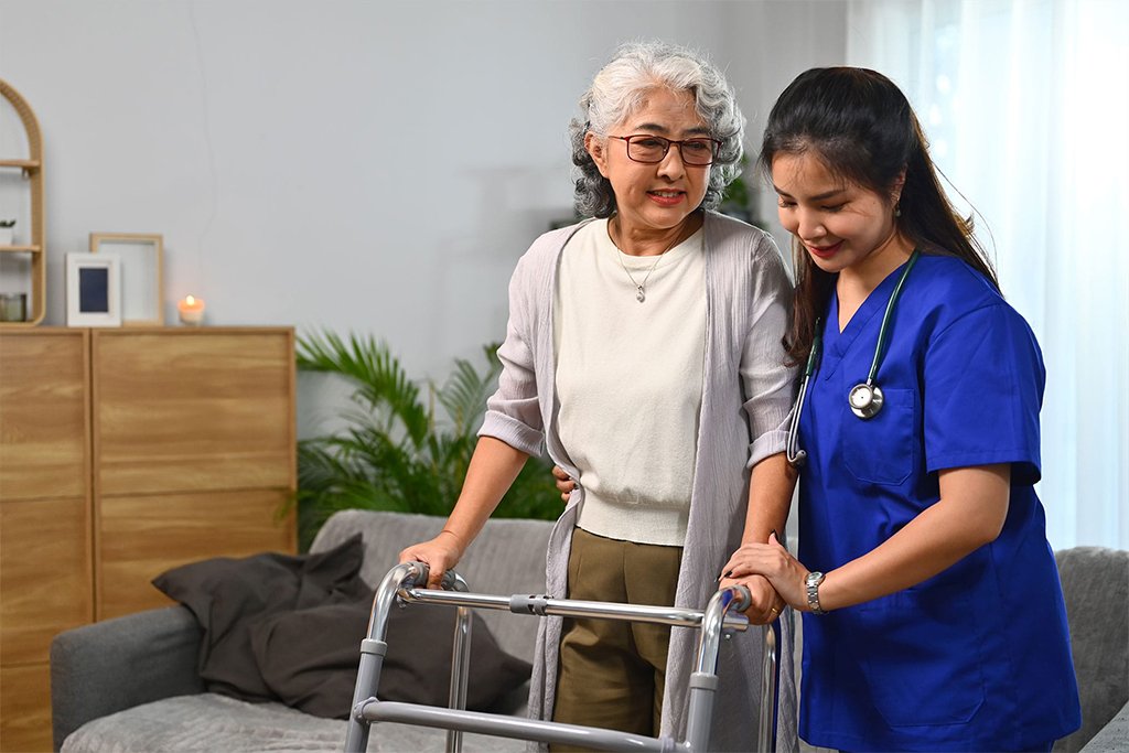 Caregiver assisting an elderly woman using a walking frame